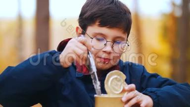 一个戴圆眼镜的男孩用刀吃炖肉罐头